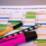 A desk setup featuring a planner, pens, and a smartphone displaying app icons, ideal for productivity.